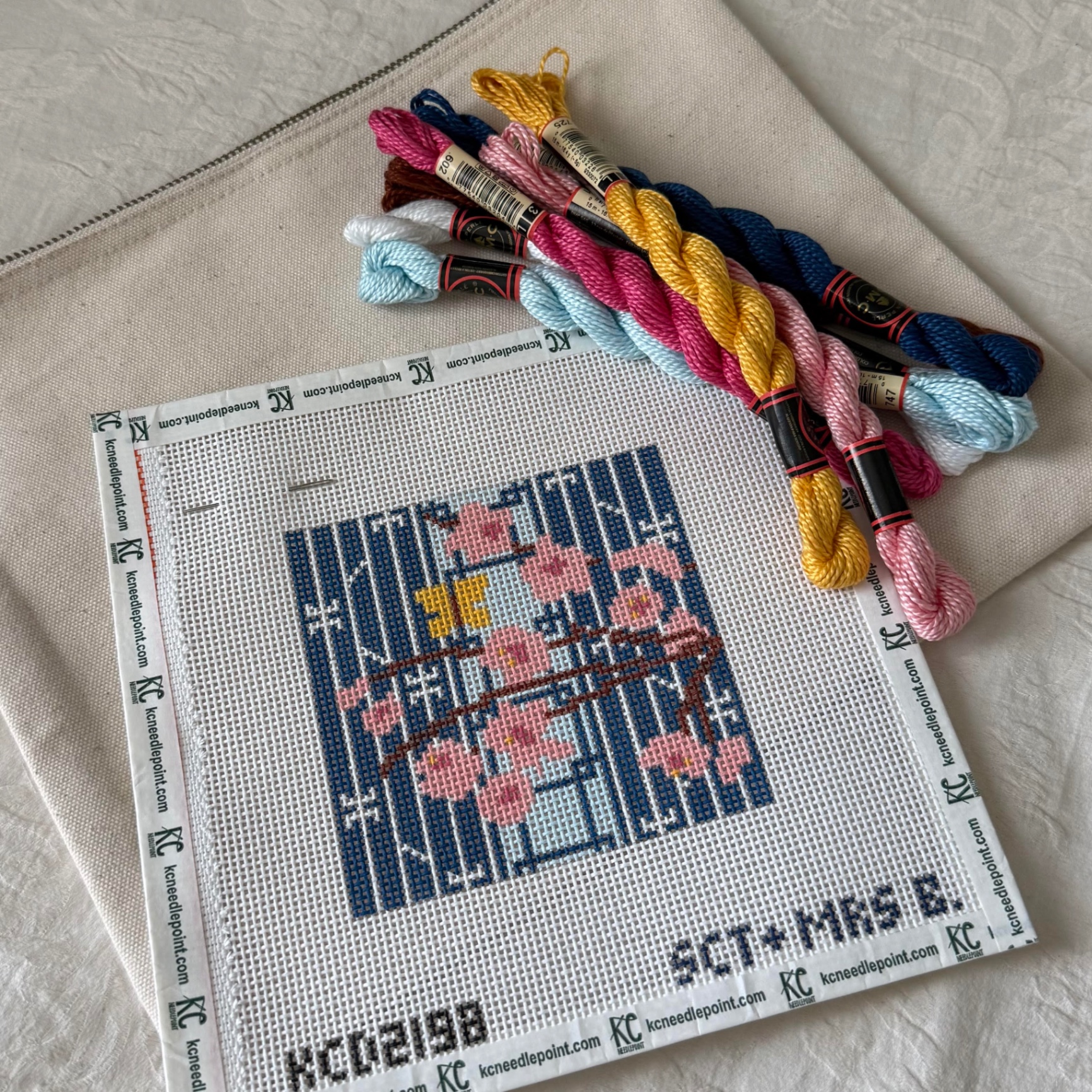 Needlepoint canvas with pink cherry blossoms and colorful threads